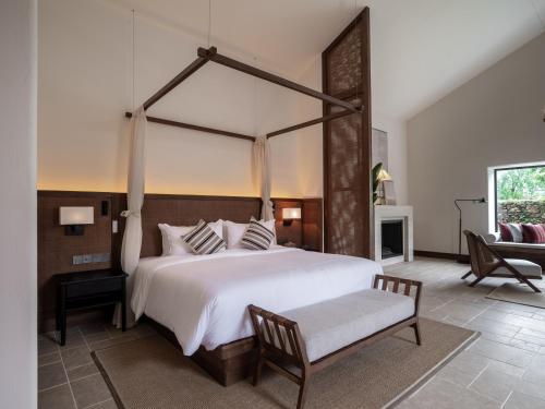 a large bedroom with a large bed and a chair at Sanhe Daoli Resort in Qingyuan