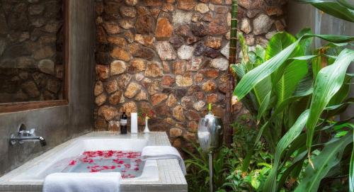 a bathroom with a bath tub with a stone wall at The Calm Oasis in Phumĭ Réach Born