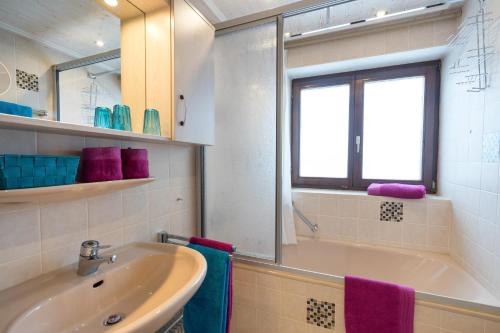 a bathroom with a sink and a tub and a window at Ferienwohnung Almwiesen in Obermaiselstein