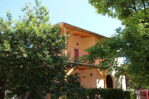 a building with a balcony in the middle of two trees at Fecskefészek Nyaralóház in Hajdúszoboszló
