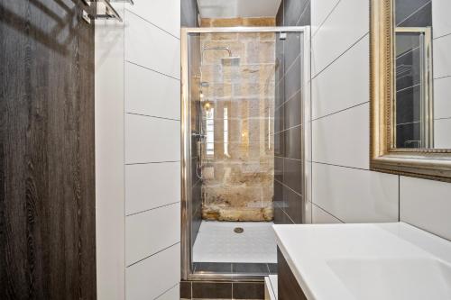 une douche avec une porte vitrée dans une salle de bain dans l'établissement La Suite Indivio - Appartement standing vue cathédrale, à Dijon