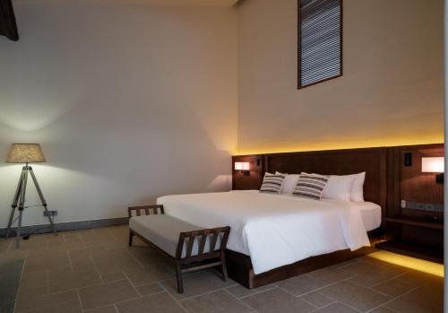 a bedroom with a large white bed and a chair at Sanhe Daoli Resort in Qingyuan