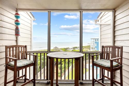uma varanda com 2 cadeiras, uma mesa e uma janela em Island Time condo em Atlantic Beach