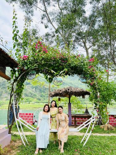 a group of three women standing under an arch with roses at Son River House in Phong Nha
