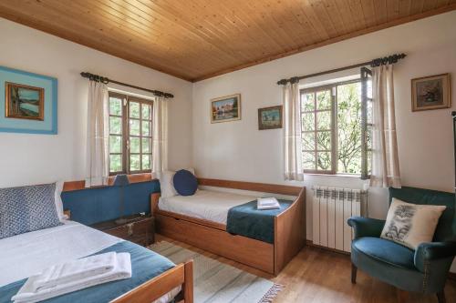 1 Schlafzimmer mit 2 Betten, einem Stuhl und Fenstern in der Unterkunft Torrinheira ~ Family Pool Villa and Woods in Travanca