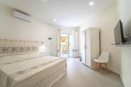 ein weißes Schlafzimmer mit einem Bett und einem Stuhl in der Unterkunft Brorent Affittacamere moro dream rooms in Olbia