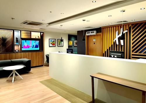 a lobby with a reception counter and a television at Holiday Inn Birmingham North - Cannock, an IHG Hotel in Cannock