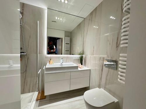 y baño con lavabo, aseo y espejo. en Shelter Luxury Apartament en Rogowo