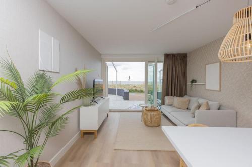 a living room with a white couch and a plant at Haya Sieview - 'The Beach' in Scheveningen