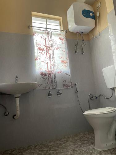 a bathroom with a toilet and a sink and a window at Keeon Private Room Back in Shillong