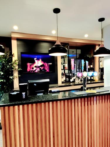a bar with a flat screen tv behind it at Holiday Inn Birmingham North - Cannock by IHG in Cannock