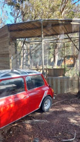 a red car parked in front of a fence at 11 Mountain Stream Hot Tub Self Catering in Gordonʼs Bay