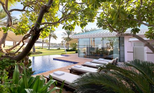 um resort com espreguiçadeiras e uma piscina em The Ritz-Carlton, Bahrain em Manama
