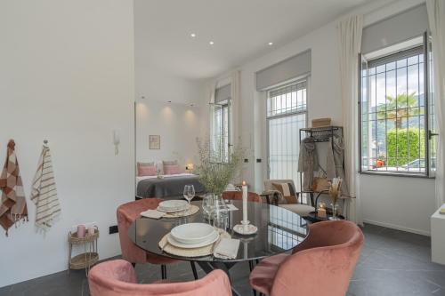 a living room with a glass table and pink chairs at Piccola Como Lotus by Rent All Como in Carate Urio