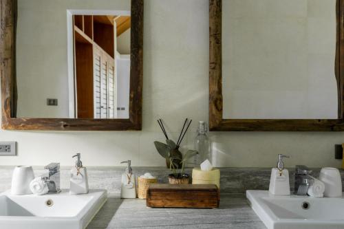 two sinks in a bathroom with two mirrors at The Cove in Panwa Beach