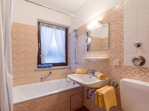 a bathroom with a sink and a tub and a mirror at Chiemgau Comfort D4 Ferienwohnanlage Oberaudorf mit Hallenbad und Sauna in Oberaudorf