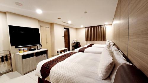 a hotel room with two beds and a flat screen tv at Sa-Yo Hotel - Pier 2 in Kaohsiung