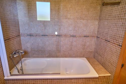 a bath tub in a tiled bathroom with a sink at Villa Almadrava in Tarragona
