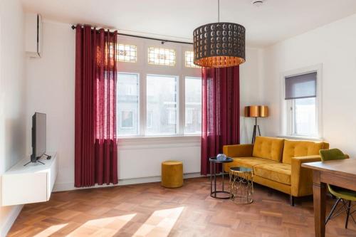 a living room with a yellow couch and red curtains at Eindhoven City Suites Hertogstraat B Modern 2P in Eindhoven