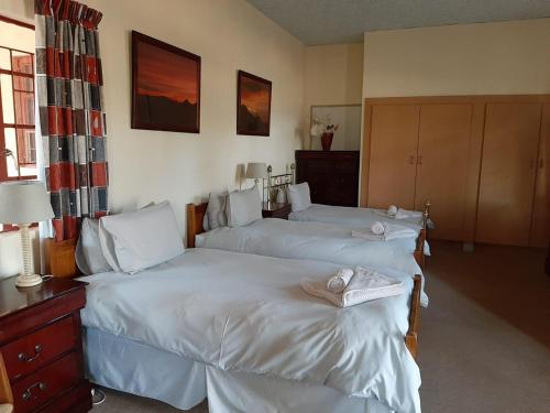 a bedroom with two beds with white sheets at Goibib Mountain Lodge in Grünau