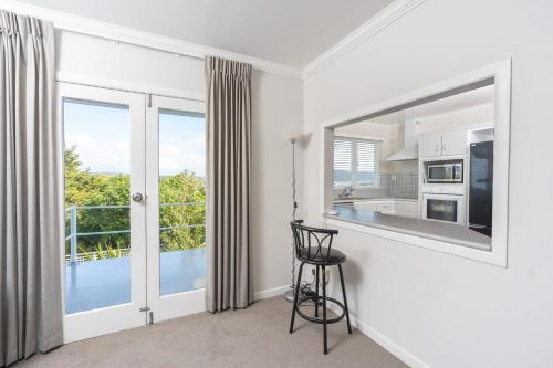 a white kitchen with a view of a balcony at Oceanview Oasis - with pool and spa in Whangarei