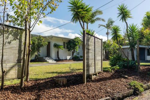 a house with a fence and palm trees at Oceanview Oasis - with pool and spa in Whangarei