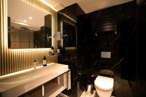 a bathroom with a sink and a toilet and a mirror at Sile Gonen Hotel in Şile