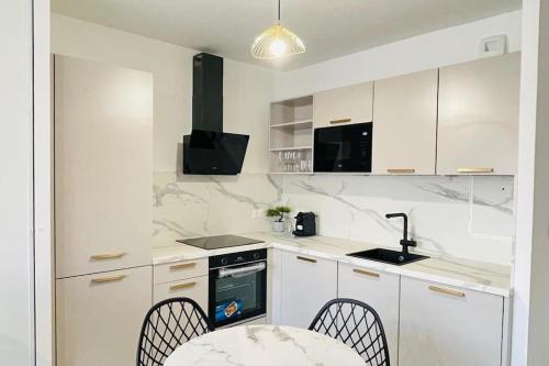 eine Küche mit weißen Schränken und einem Tisch und Stühlen in der Unterkunft Bel appartement à 5 mn de Paris très proche Métro 13 et 14 in Saint-Ouen