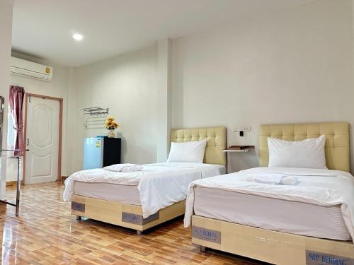 dos camas sentadas una al lado de la otra en un dormitorio en โรงแรม ปาล์มเพลส en Ban Wang Phai Tha Kham
