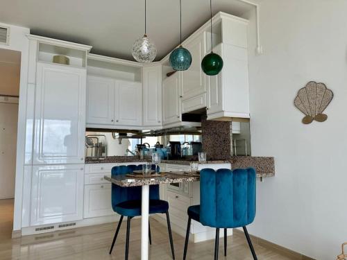 - une cuisine avec des placards blancs et des chaises bleues dans l'établissement Splendide vue mer, proche centre Beausoleil, à Beausoleil
