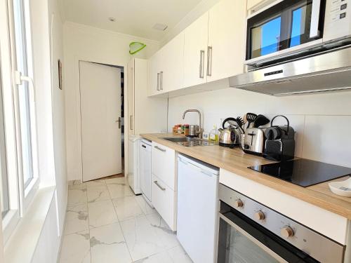 une cuisine avec des armoires blanches et un comptoir dans l'établissement 2 Pièces, face casino, 20 mètres plage, wifi., à Trouville-sur-Mer