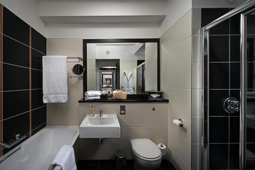 a bathroom with a sink and a toilet and a tub at Carlton Hotel Blanchardstown in Blanchardstown