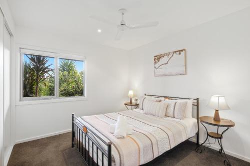 a white bedroom with a bed and a window at Saltwater Breeze Retreat in Cowes