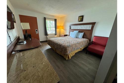 Habitación de hotel con cama y silla roja en Southern Inn By OYO Walterboro I-95, en Walterboro