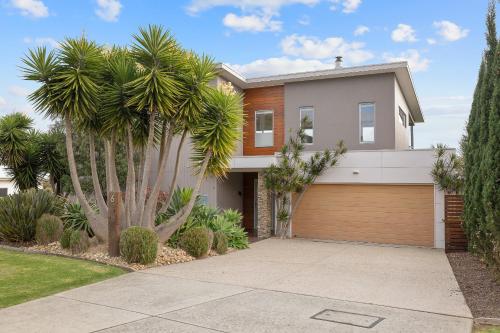 a house with palm trees in front of a driveway at Saltwater Breeze Retreat in Cowes