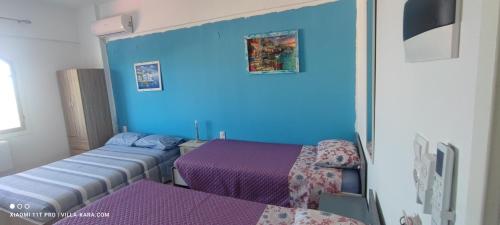 um quarto com duas camas e uma parede azul em VILLA KARA - Bed and Breakfast em Mési