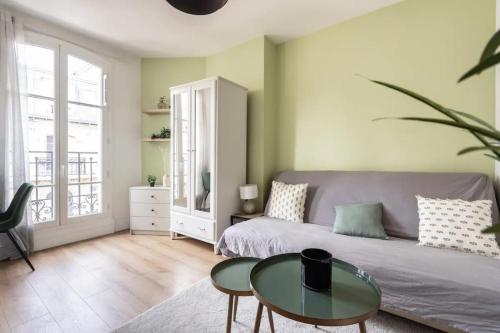 een woonkamer met een bank en een tafel bij Cocon aux portes de Paris in Clichy