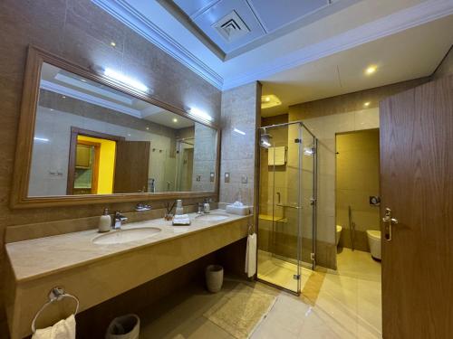 a bathroom with a sink and a mirror and a shower at Al Hamra golf & sea resort lagoon view suite in Ras al Khaimah