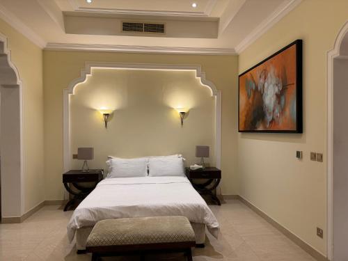 a bedroom with a large bed with two tables and a painting at Al Hamra golf & sea resort lagoon view suite in Ras al Khaimah