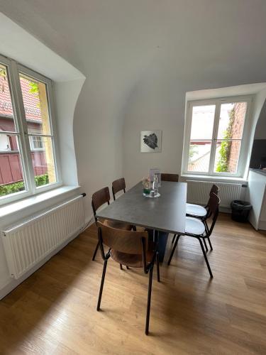 a dining room with a table and chairs and two windows at Hopfenhotel am Adenauerufer in Bamberg