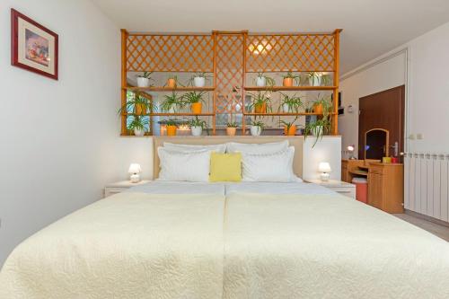 Studio Apartment Oliva في بولا: غرفة نوم مع سرير أبيض كبير مع نباتات على الأرفف
