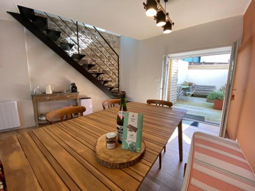 a dining room with a wooden table with a bottle of wine at ty_yaouen maison de vacances in Carantec