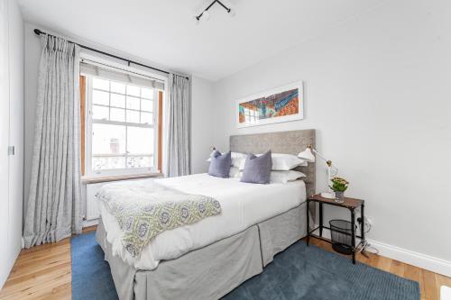 Un dormitorio blanco con una cama grande y una ventana en Munster Village in Fulham, en Londres