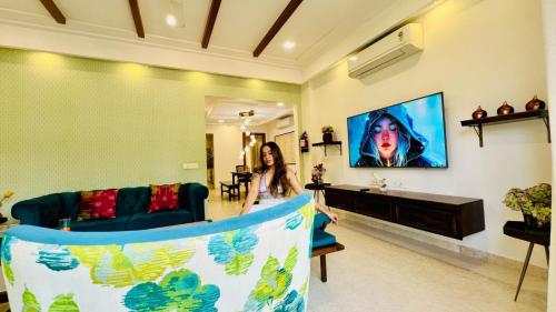 a woman walking through a living room with a tv at BluO Luxury Stay - Medicity - Balcony, Tub, Gym TT in Gurgaon