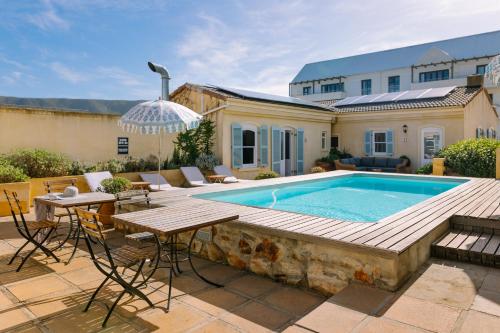 un cortile con piscina, tavolo e sedie di Auberge Burgundy Boutique Hotel & Spa a Hermanus