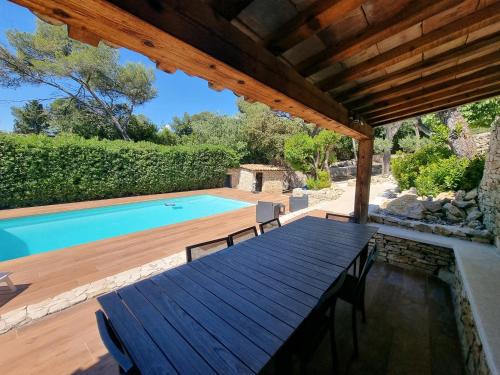 a patio with a wooden table and a swimming pool at Villa THAÏS in Nîmes