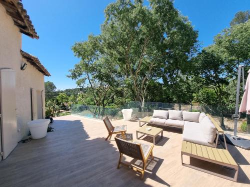 a patio with a couch and chairs and trees at Villa THAÏS in Nîmes