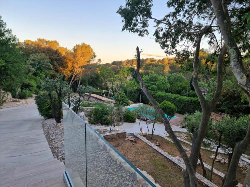 a fence overlooking a garden with a pool and trees at Villa THAÏS in Nîmes