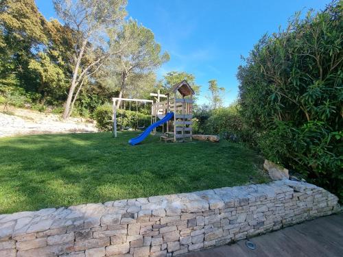 a playground with a slide in a yard at Villa THAÏS in Nîmes