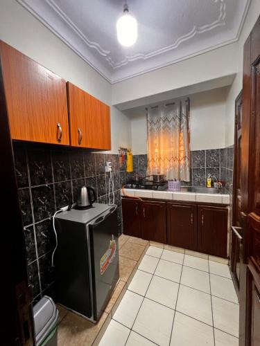 a kitchen with a black refrigerator and wooden cabinets at Studio room entebbe in Entebbe